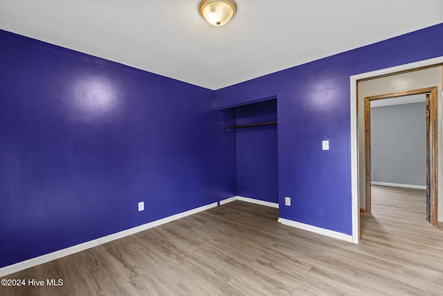 unfurnished bedroom featuring a closet, hardwood / wood-style floors, and a textured ceiling