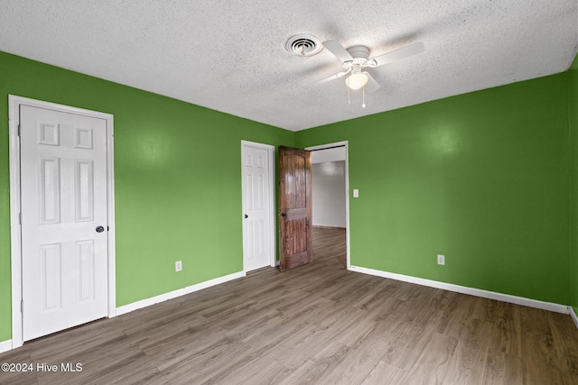 unfurnished bedroom with wood-type flooring, a textured ceiling, and ceiling fan