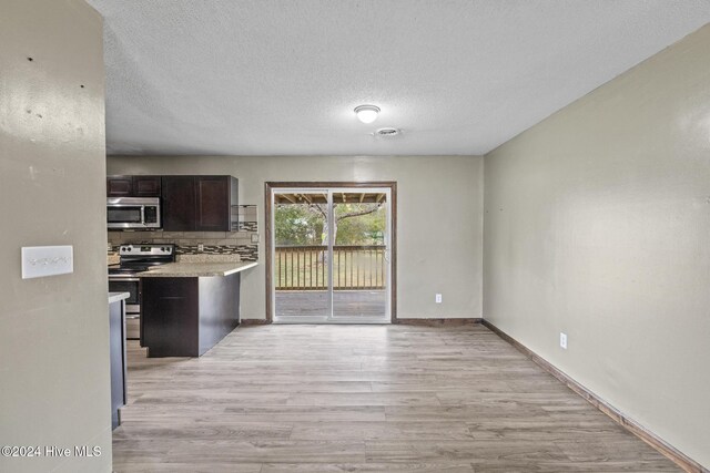 kitchen with stainless steel appliances, tasteful backsplash, light hardwood / wood-style floors, a textured ceiling, and dark brown cabinets