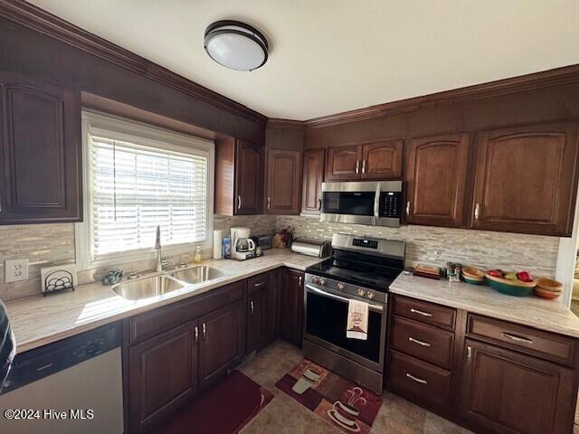 kitchen featuring dark brown cabinets, sink, ornamental molding, and stainless steel appliances