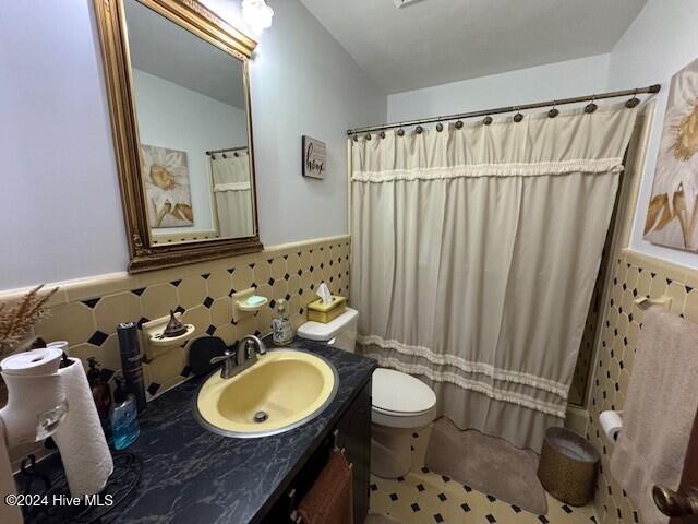 bathroom with a shower with shower curtain, vanity, toilet, and tile patterned flooring