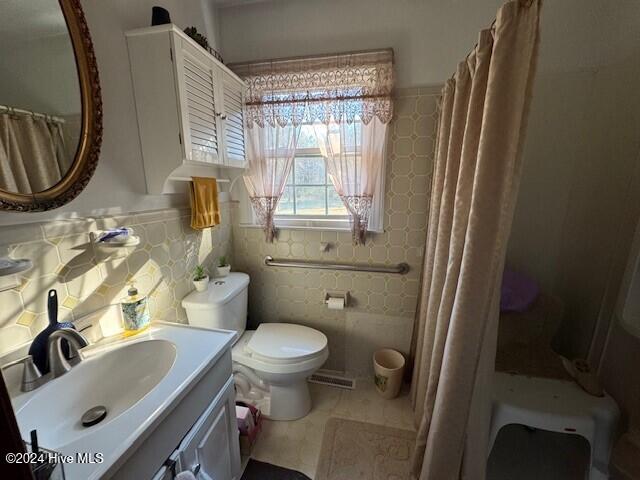 bathroom featuring tasteful backsplash, tile patterned floors, vanity, tile walls, and toilet