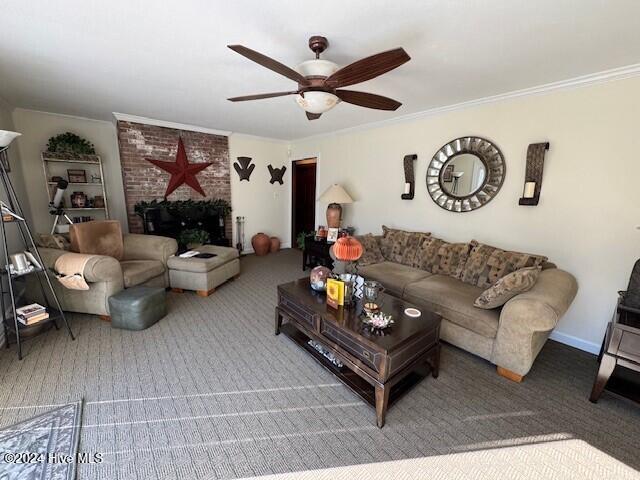 living room featuring carpet flooring, ceiling fan, crown molding, and a brick fireplace