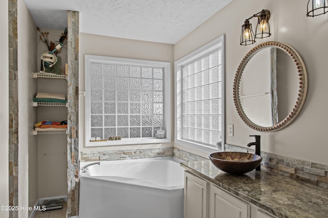 bathroom featuring plenty of natural light, a washtub, vanity, and a textured ceiling