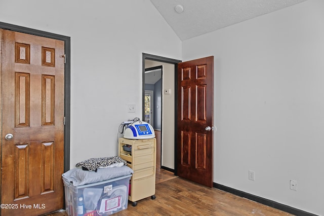 bedroom with a textured ceiling, dark wood-type flooring, and lofted ceiling