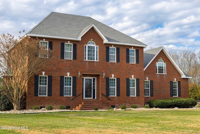 colonial-style house featuring a front lawn