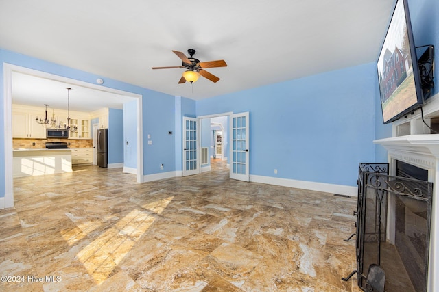 living room with french doors and ceiling fan with notable chandelier