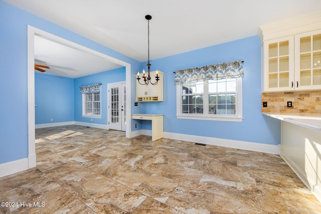 unfurnished dining area featuring ceiling fan with notable chandelier