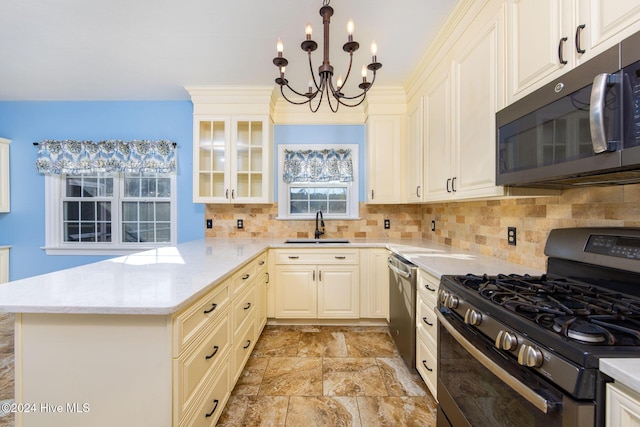 kitchen with an inviting chandelier, sink, tasteful backsplash, kitchen peninsula, and stainless steel appliances