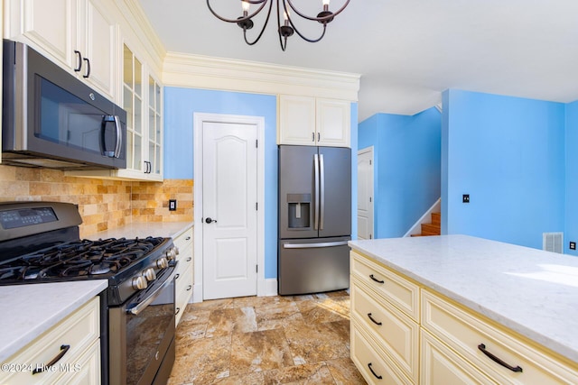 kitchen with decorative backsplash, light stone counters, stainless steel appliances, and a chandelier