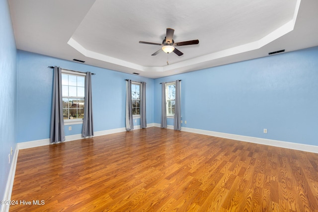 unfurnished room with a raised ceiling, ceiling fan, and hardwood / wood-style floors