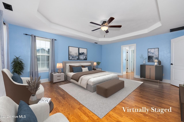 bedroom featuring dark hardwood / wood-style floors, ceiling fan, and a tray ceiling