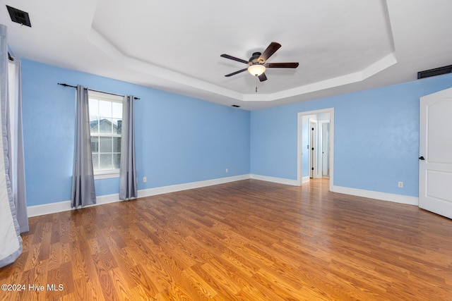 spare room with ceiling fan, wood-type flooring, and a tray ceiling