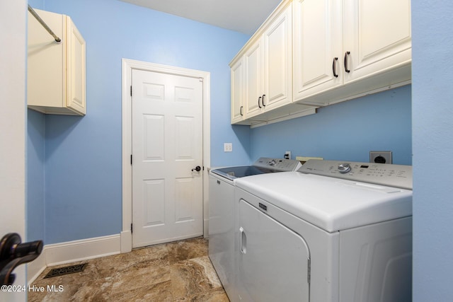 laundry room featuring washer and clothes dryer and cabinets