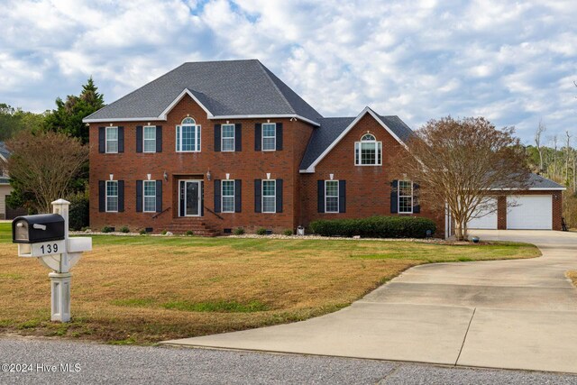 colonial inspired home featuring a front lawn and a garage