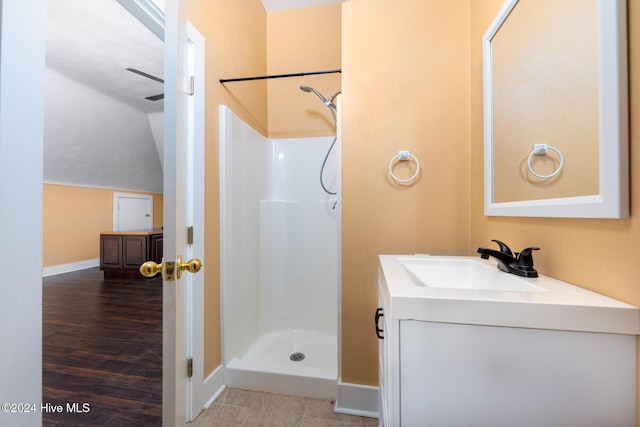 bathroom with a shower, vanity, lofted ceiling, and hardwood / wood-style flooring