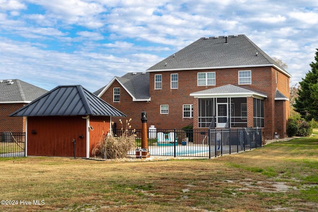 rear view of property featuring a fenced in pool, a sunroom, and a yard