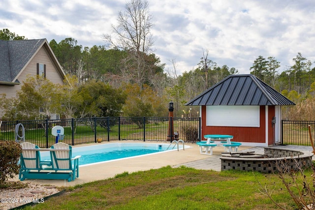 view of swimming pool featuring a lawn, a patio, and an outdoor fire pit