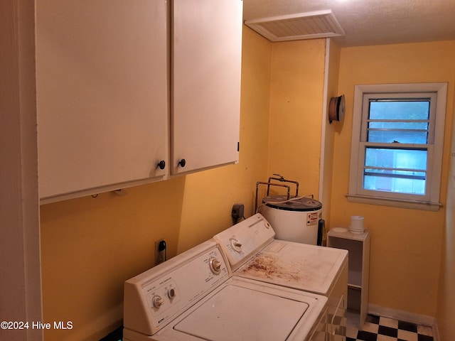 washroom featuring cabinets, washing machine and dryer, electric water heater, and a textured ceiling