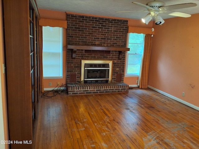 unfurnished living room featuring a fireplace, wood-type flooring, and ceiling fan