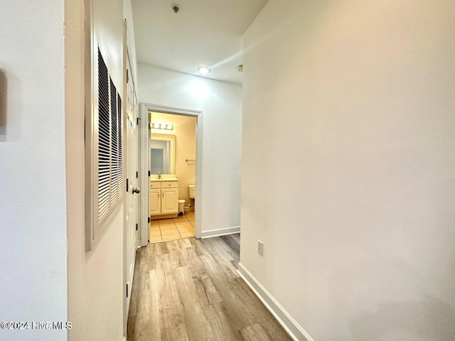 corridor with light wood-type flooring and sink