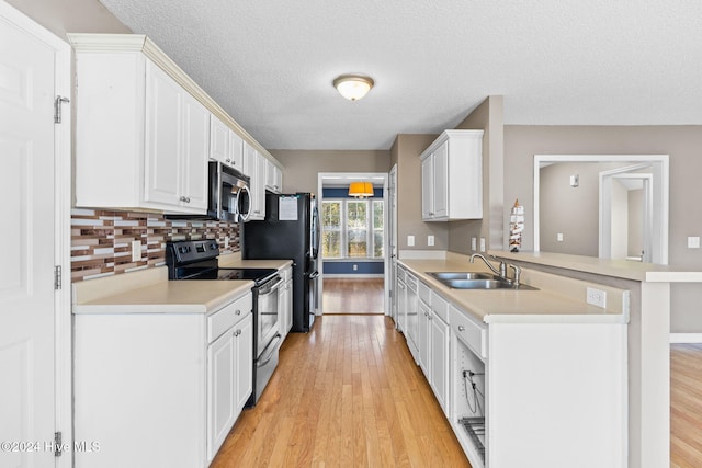 kitchen with kitchen peninsula, appliances with stainless steel finishes, light hardwood / wood-style flooring, and white cabinetry