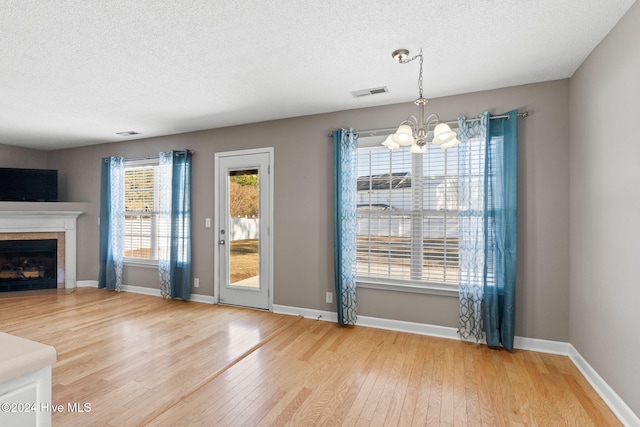 unfurnished living room featuring wood-type flooring, a textured ceiling, and an inviting chandelier