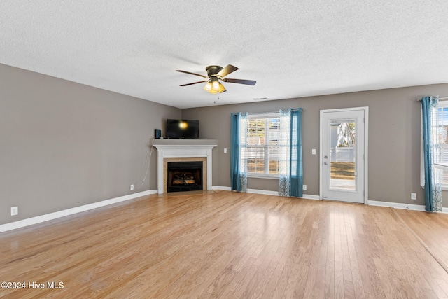 unfurnished living room featuring a textured ceiling, light hardwood / wood-style floors, a wealth of natural light, and ceiling fan