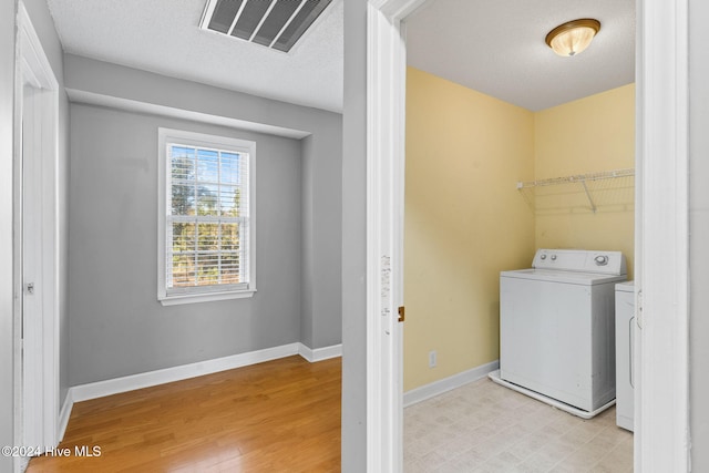 washroom with washer / dryer, a textured ceiling, and light hardwood / wood-style flooring