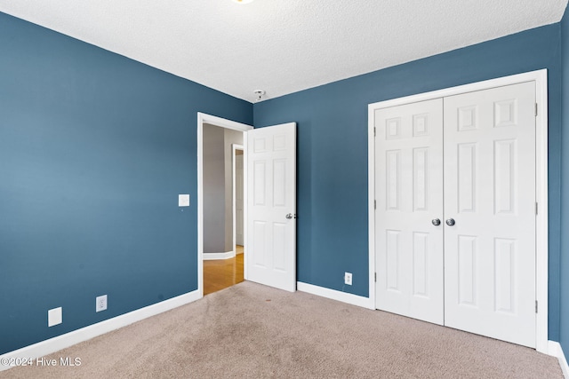 unfurnished bedroom featuring carpet floors, a textured ceiling, and a closet