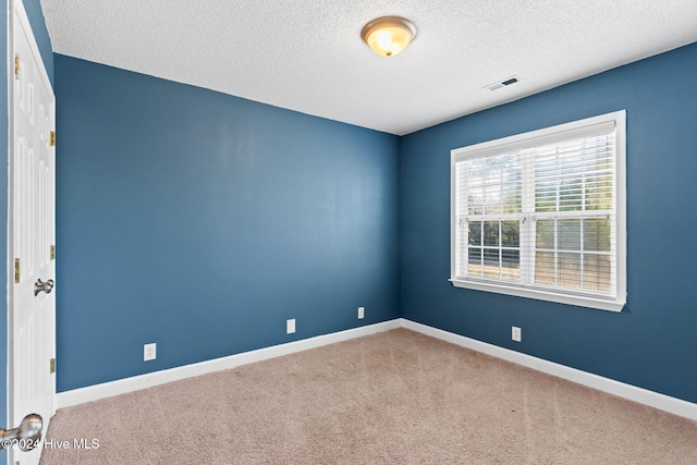 carpeted empty room with a textured ceiling