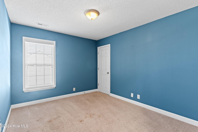 unfurnished room featuring light colored carpet and a textured ceiling