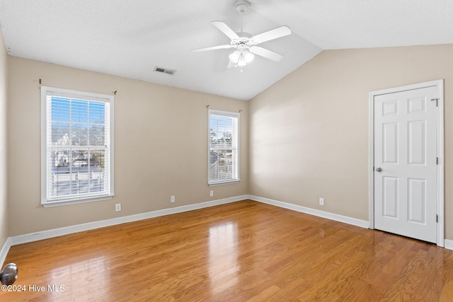 spare room with vaulted ceiling, light hardwood / wood-style flooring, ceiling fan, and a healthy amount of sunlight