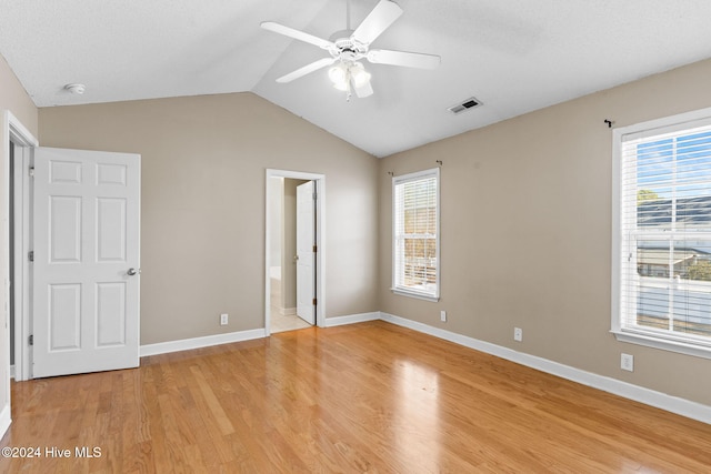 unfurnished bedroom featuring ceiling fan, light wood-type flooring, ensuite bathroom, and multiple windows