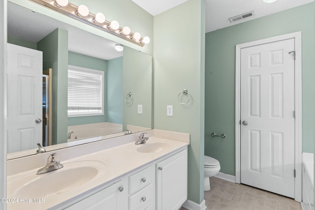 bathroom featuring a washtub, toilet, a textured ceiling, and vanity