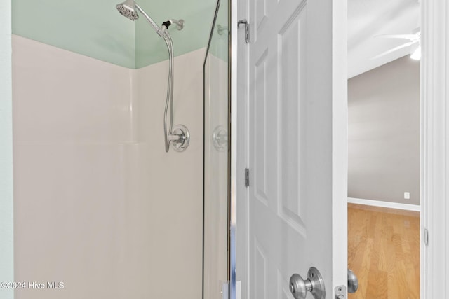 bathroom featuring ceiling fan, wood-type flooring, and a shower with door