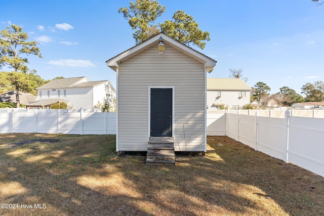 rear view of house featuring a lawn and a storage shed