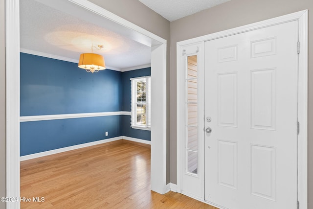 entryway featuring hardwood / wood-style floors, a textured ceiling, and crown molding