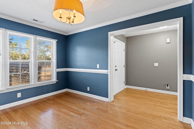 unfurnished room with a notable chandelier, crown molding, wood-type flooring, and a textured ceiling