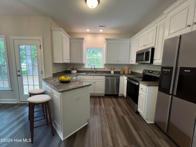 kitchen featuring white cabinets, a kitchen breakfast bar, sink, dark hardwood / wood-style flooring, and stainless steel appliances