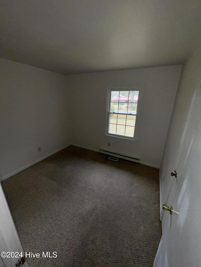 empty room featuring carpet floors and a baseboard heating unit