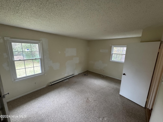 carpeted spare room featuring a textured ceiling and a baseboard heating unit