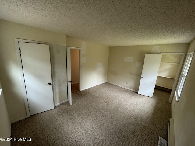 unfurnished bedroom with carpet, a textured ceiling, and a closet