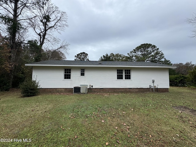 rear view of property with a yard and central AC unit