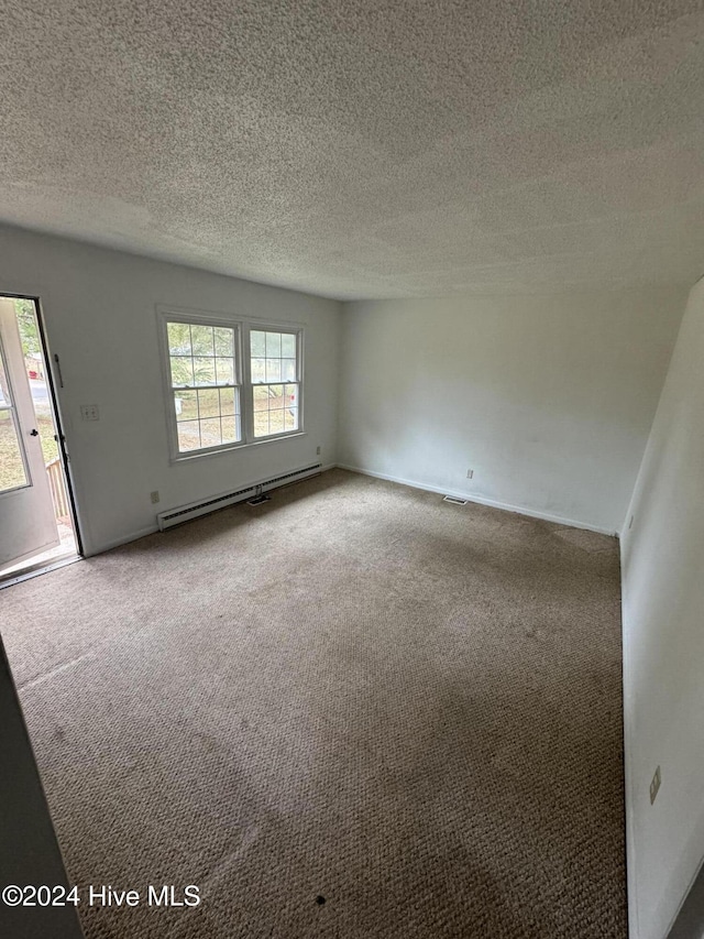 carpeted spare room with a textured ceiling and baseboard heating