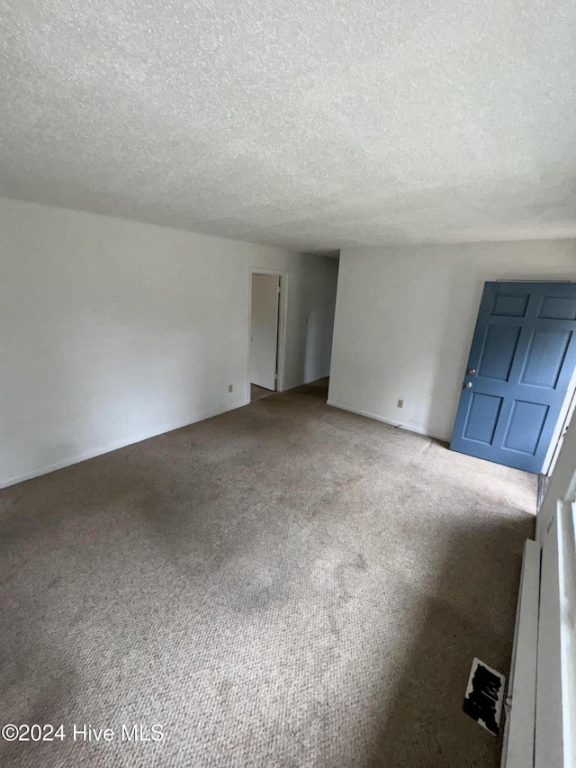 unfurnished living room featuring carpet floors and a textured ceiling