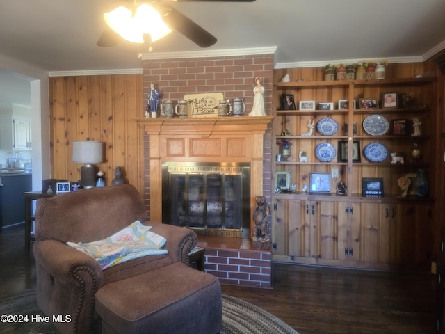 living room with wood walls, ornamental molding, dark wood-type flooring, and a brick fireplace