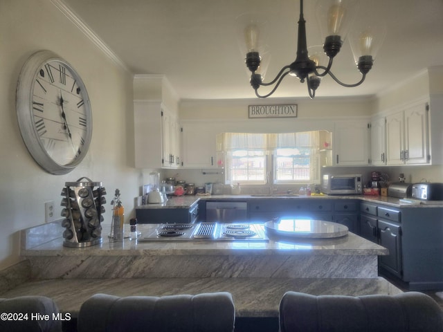 kitchen featuring sink, ornamental molding, appliances with stainless steel finishes, a notable chandelier, and white cabinetry