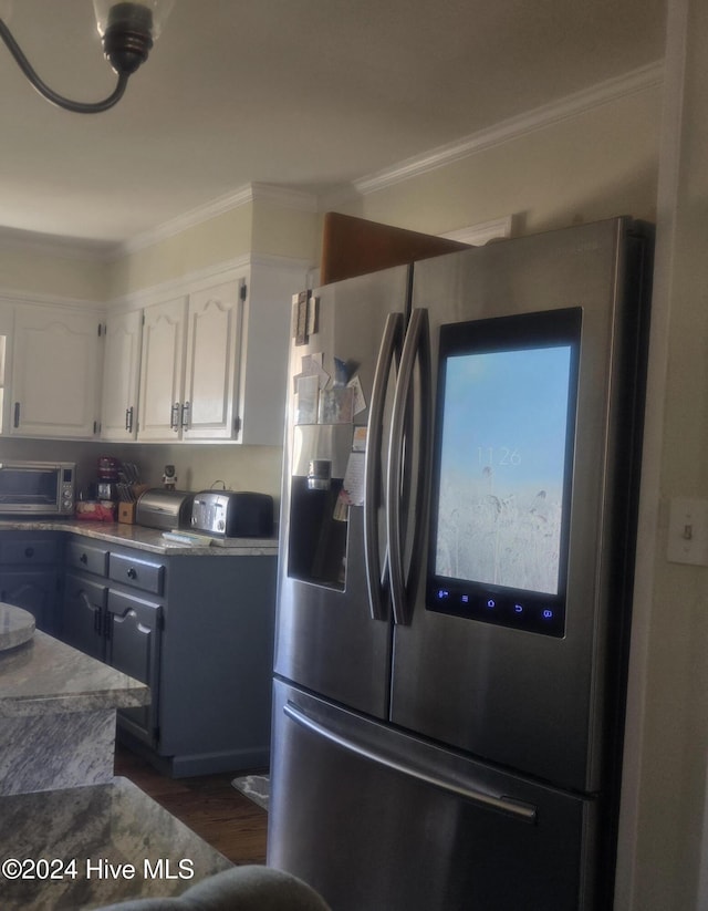 kitchen with white cabinetry, stainless steel fridge, dark wood-type flooring, and ornamental molding