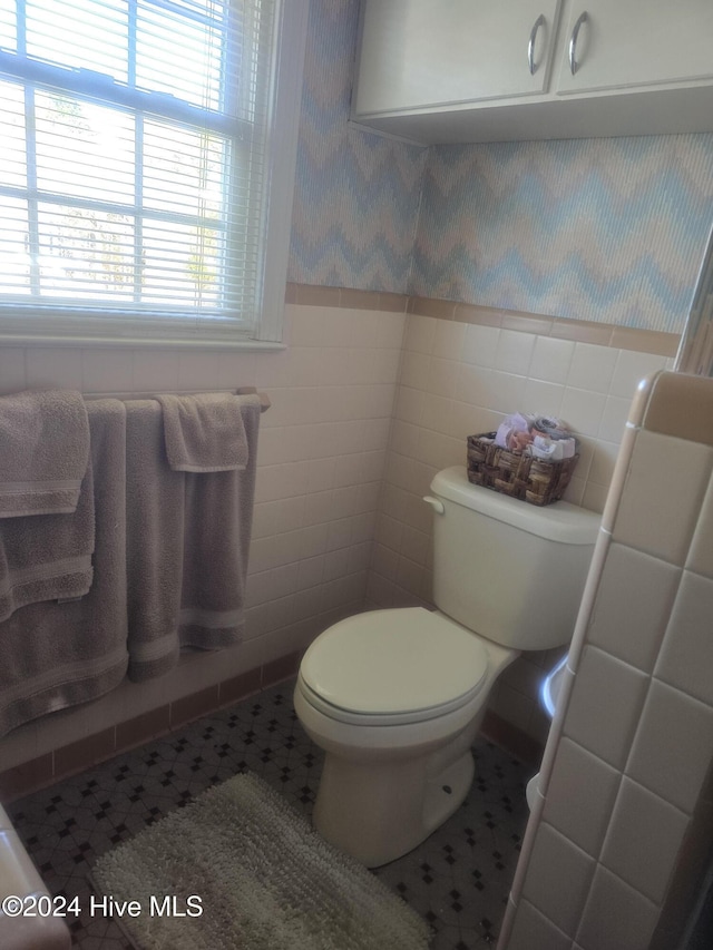 bathroom featuring tile patterned floors, tile walls, and toilet